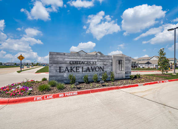 A sign for Cottages at Lake Lavon is displayed in front of a building.