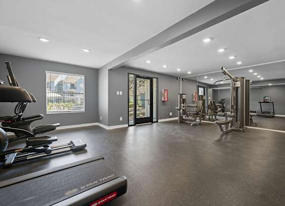 A spacious home gym with a treadmill, elliptical machines, and other exercise equipment.