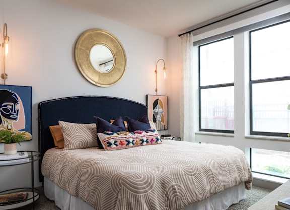 A bedroom with a large bed and a round mirror on the wall.