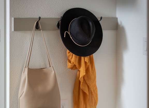 A black hat and a mustard yellow scarf are hanging on a hook.