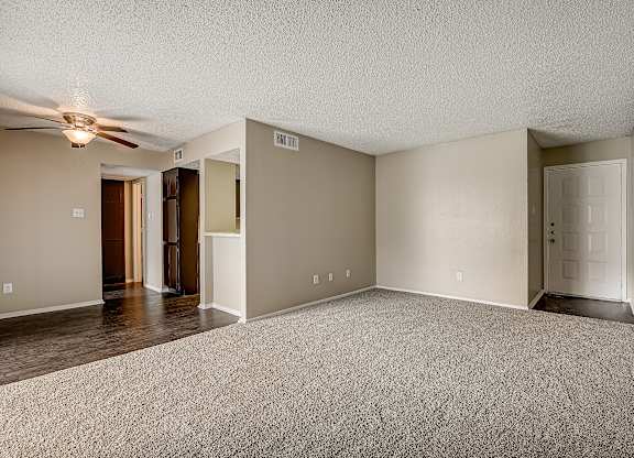 an empty living room with a ceiling fan