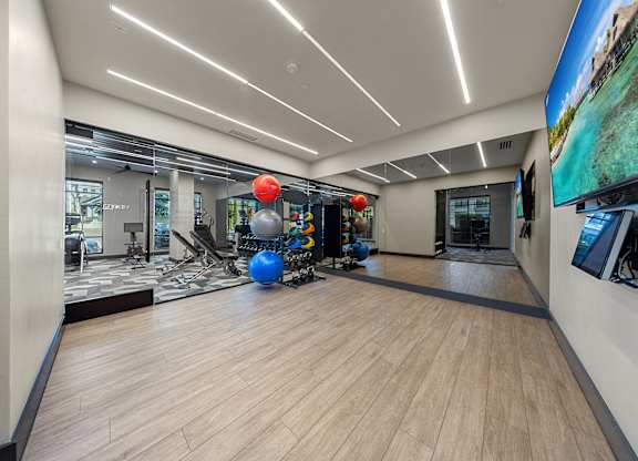 A spacious room with wooden flooring and a large screen on the wall.