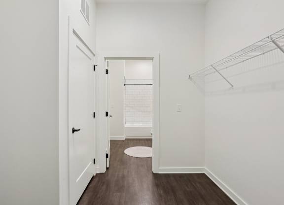 A white hallway with a door and a round rug on the floor.