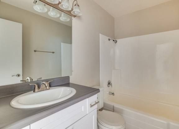 A bathroom with a sink, toilet, and bathtub.