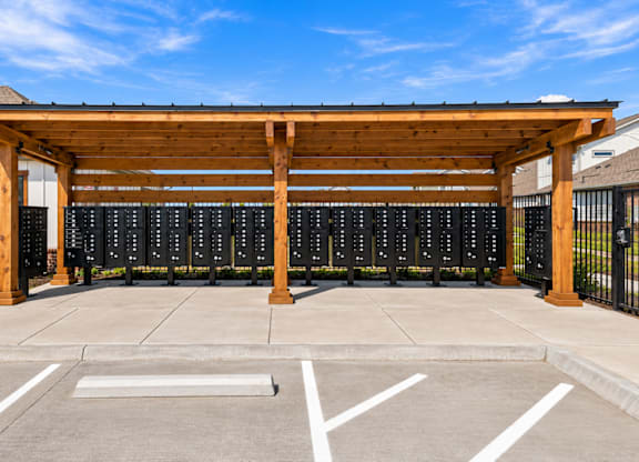 A parking lot with a wooden canopy and a row of black mailboxes.
