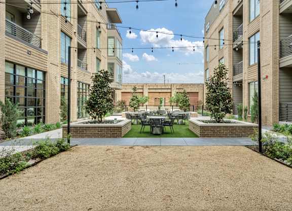 A courtyard surrounded by buildings with a table and chairs in the middle.