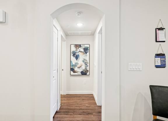 A hallway with a chair and a painting on the wall.