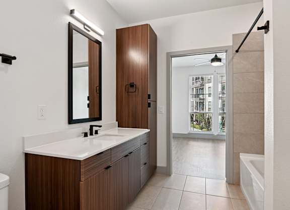 A bathroom with a white sink and brown cabinetry.