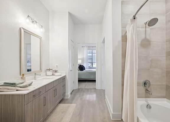 A bathroom with a white tub, sink, and shower.