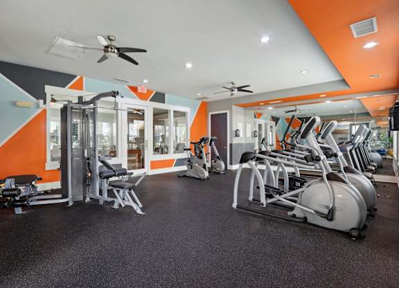 A gym with orange walls and a variety of equipment.
