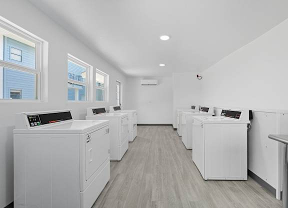 A row of white washing machines are lined up in a laundry room.