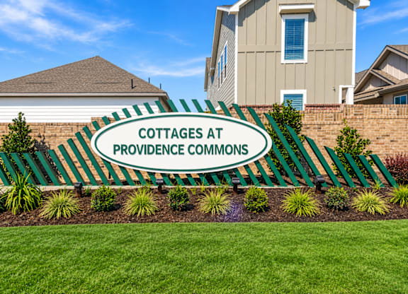 A sign that says Cottages at Providence Commons in front of a building.