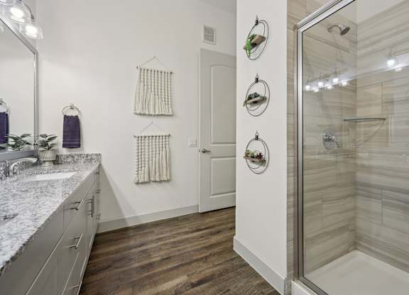Spacious bathroom with tiled standing shower, large countertops, and bright lighting.