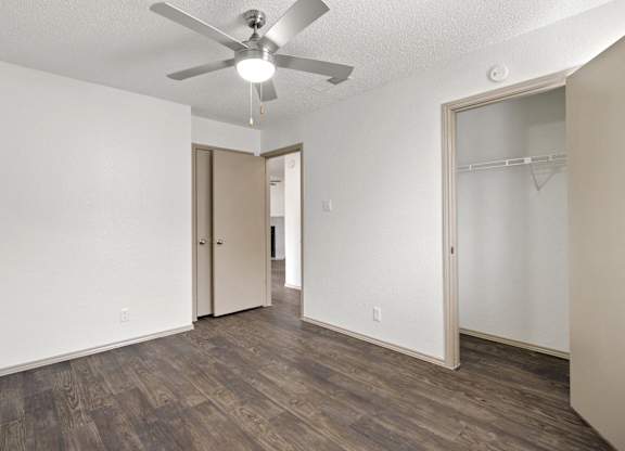 A room with a ceiling fan and wood flooring.