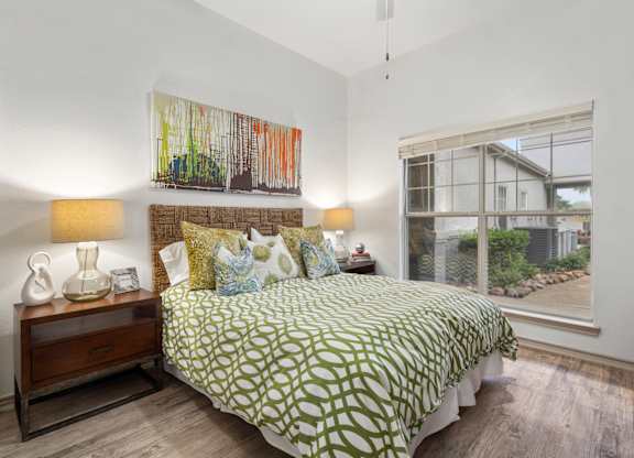 A bedroom with a bed, nightstand, and a painting on the wall.