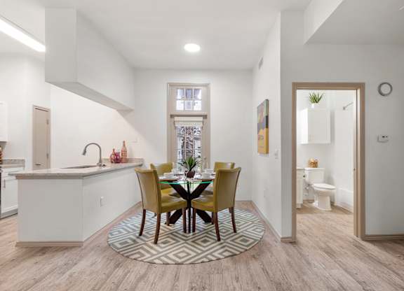 A kitchen with a dining table and chairs in the middle.