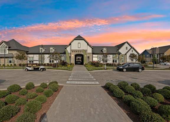 A large building with the word "MANOR" on it is surrounded by a parking lot.