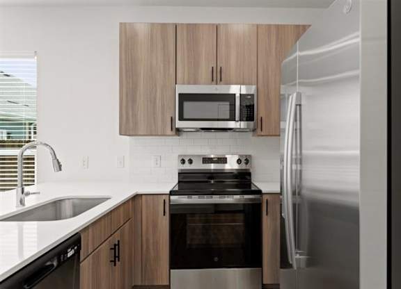 A modern kitchen with a stainless steel refrigerator, microwave, and oven.