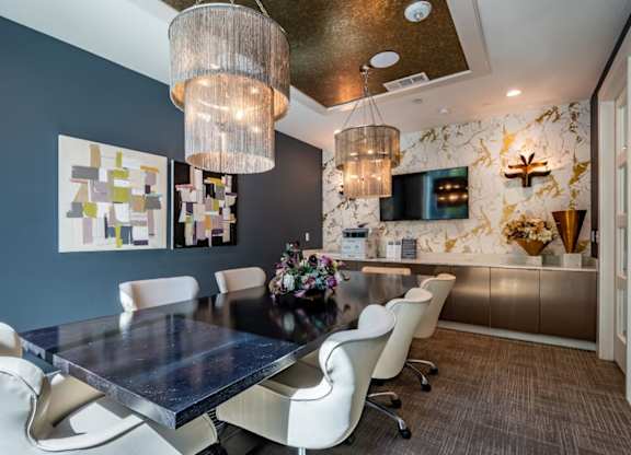 A modern dining room with a dark table and white chairs.
