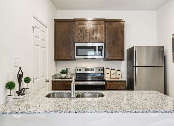 A kitchen with a granite countertop and stainless steel appliances.