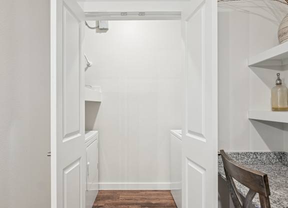 A white hallway with a wooden floor and a chair on the right side.