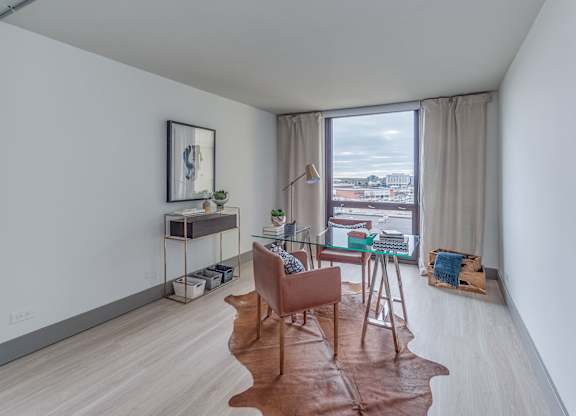 A room with a brown leather chair and a glass table with a plant on it.