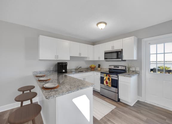a kitchen with white cabinets and a granite counter top and a stove