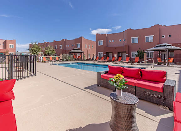 A pool area with red couches and a table with flowers on it.