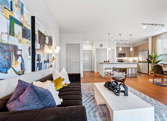 A modern living room with a brown couch and a large abstract painting on the wall.