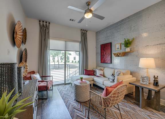 A living room with a sofa, chairs, and a ceiling fan.