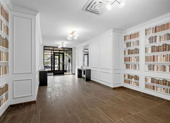 A room with white bookshelves filled with books.