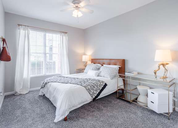 A bedroom with a bed, nightstand, and window.