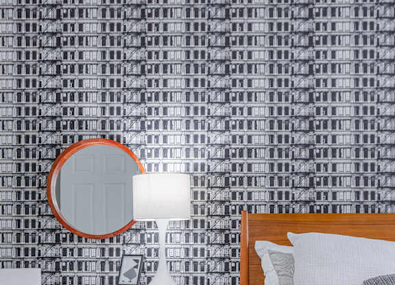 A bedroom with a bed, chair, and a mirror.