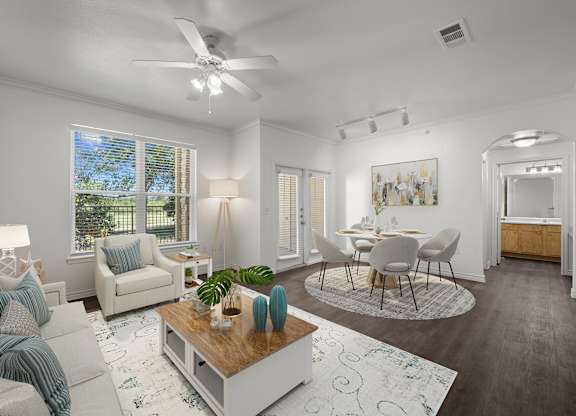 a living room and dining room with white furniture and a ceiling fan