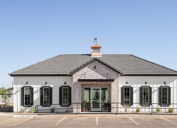 A white building with black shutters and a brick chimney.