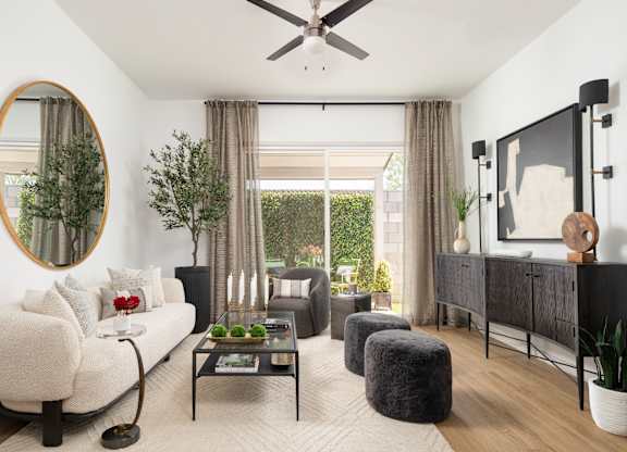 A living room with a white couch, a coffee table, and a large mirror on the wall.