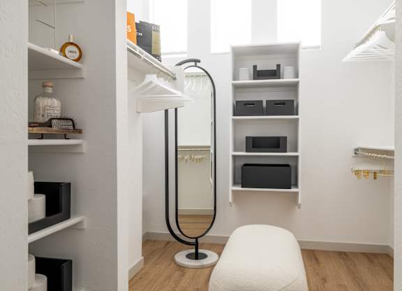 A white chair sits in a room with white walls and wood floors.