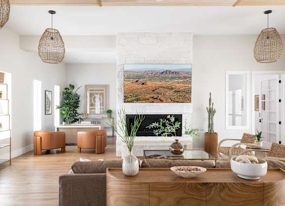 A living room with a large painting of a desert landscape on the wall.