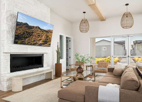 A living room with a fireplace and a large screen TV mounted on the wall.