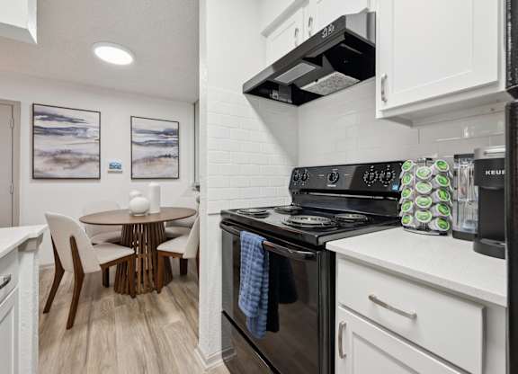 A modern kitchen with a black stove top oven and white cabinets.