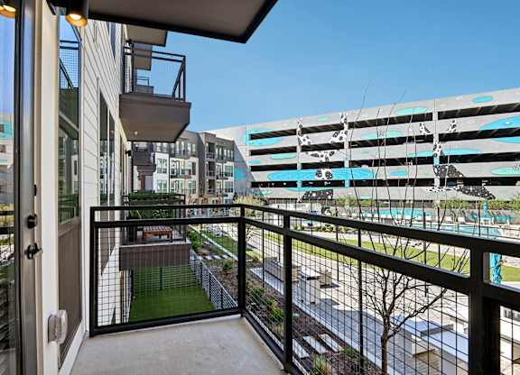 A balcony with a view of a pool and buildings.