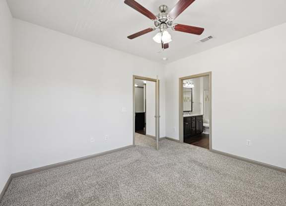 A room with a ceiling fan and carpeted floor.
