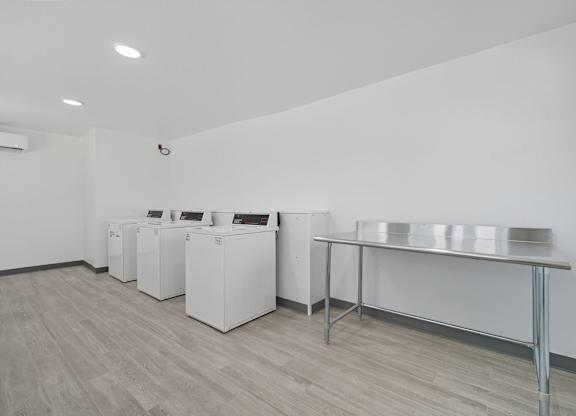 A white room with a table and a couple of washing machines.