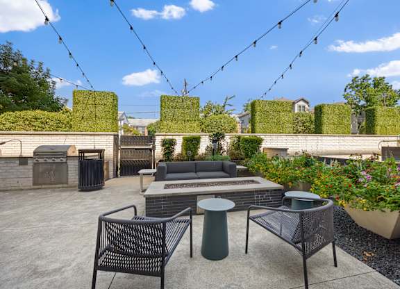A patio with a table, chairs, and a planter.