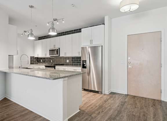 A kitchen with a refrigerator, microwave, and oven.