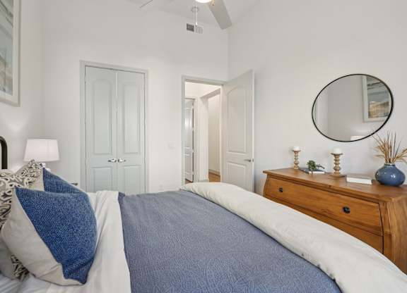 A bedroom with a bed, a dresser, and a mirror.
