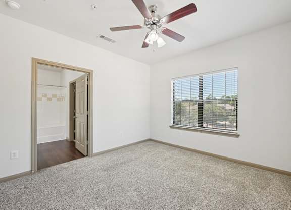 A room with a ceiling fan and a window with blinds.