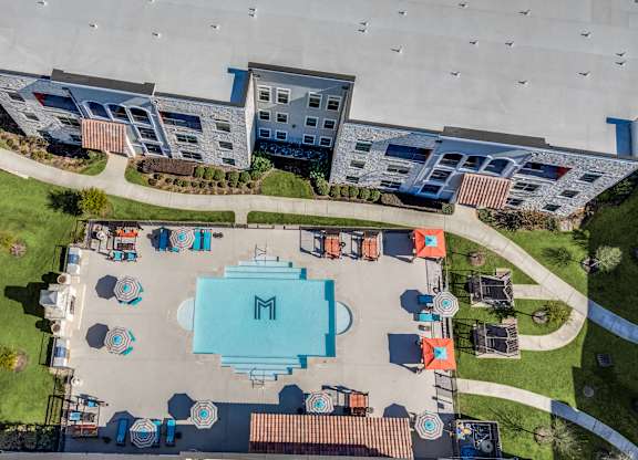 An aerial view of a swimming pool surrounded by lounge chairs and umbrellas.