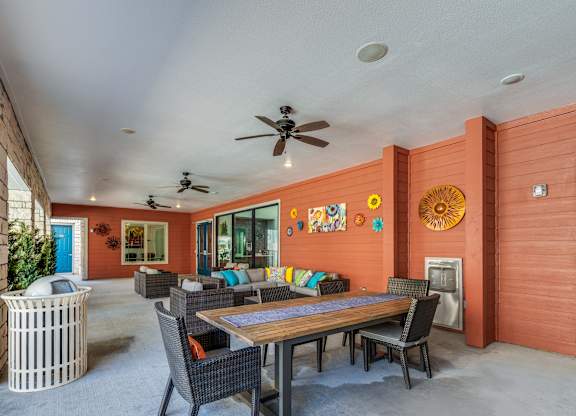 A patio with a table and chairs and a ceiling fan.