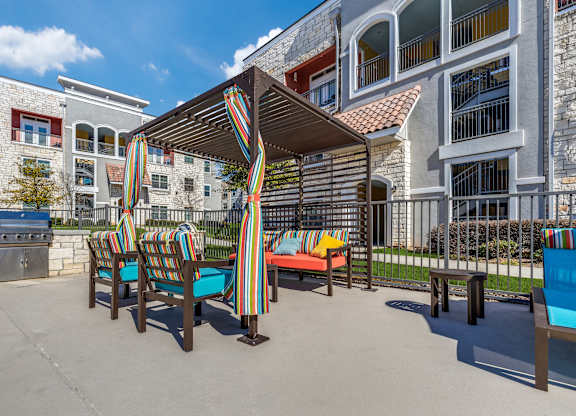 A patio with a striped awning and striped chairs.